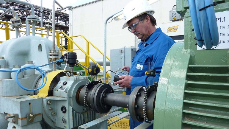 Field engineer performing laser shaft alignment on a pump and motor train